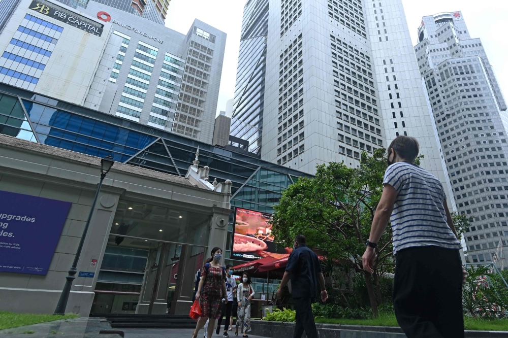 People walk along promenade during lunch break at Raffles Place financial business district in Singapore on June 15, 2020. AFP / Roslan RAHMAN