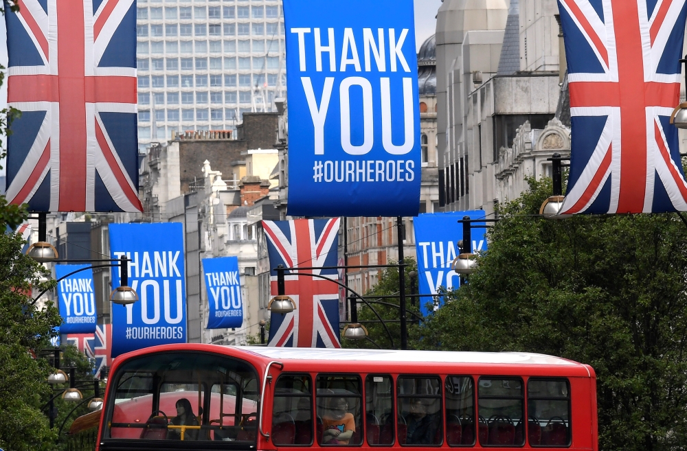 A bus is seen passing underneath Union Jack flags and banners with a message reading 
