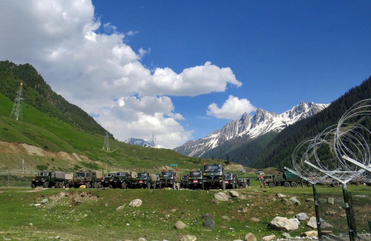 Indian army soldiers walk past their parked trucks at a makeshift transit camp before heading to Ladakh, near Baltal, southeast of Srinagar, June 16, 2020. REUTERS/Stringer
