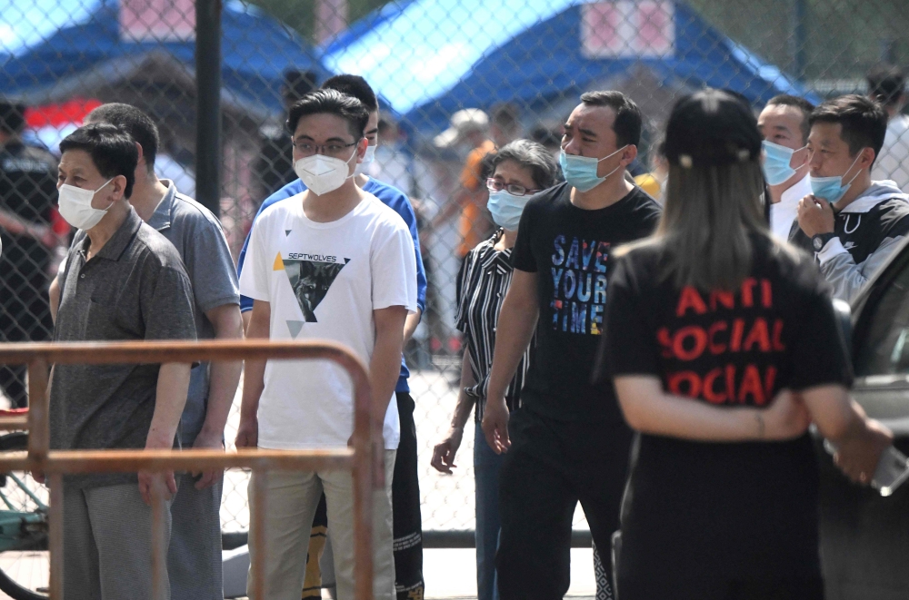 People wearing face masks wait to take a swab test for the COVID-19 coronavirus as officials conduct mass testing following a new cluster of cases last week, in Beijing on June 18, 2020. Beijing reported another 21 cases of the coronavirus on June 18, as 