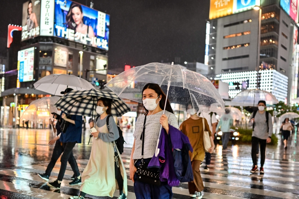 Pedestrians walk with umbrellas as evening rain falls in Tokyo on June 19, 2020. / AFP / CHARLY TRIBALLEAU