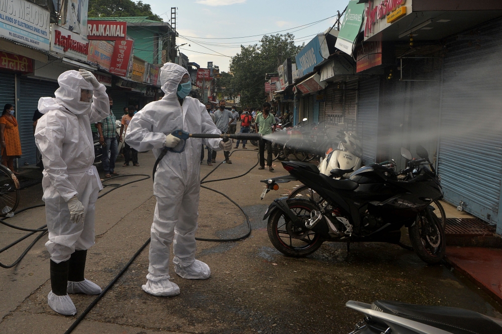 Firefighters wearing Personal Protective Equipment (PPE) spray disinfectant in a closed market amid concerns over the spread of the COVID-19 coronavirus in Siliguri on June 22, 2020. AFP / Diptendu Dutta 