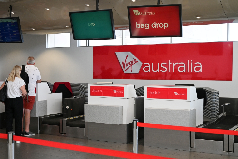 Travelers stand at a Virgin Australia Airlines counter at Kingsford Smith International Airport, following the coronavirus outbreak, in Sydney, Australia, March 18, 2020. REUTERS/Loren Elliott/File Photo