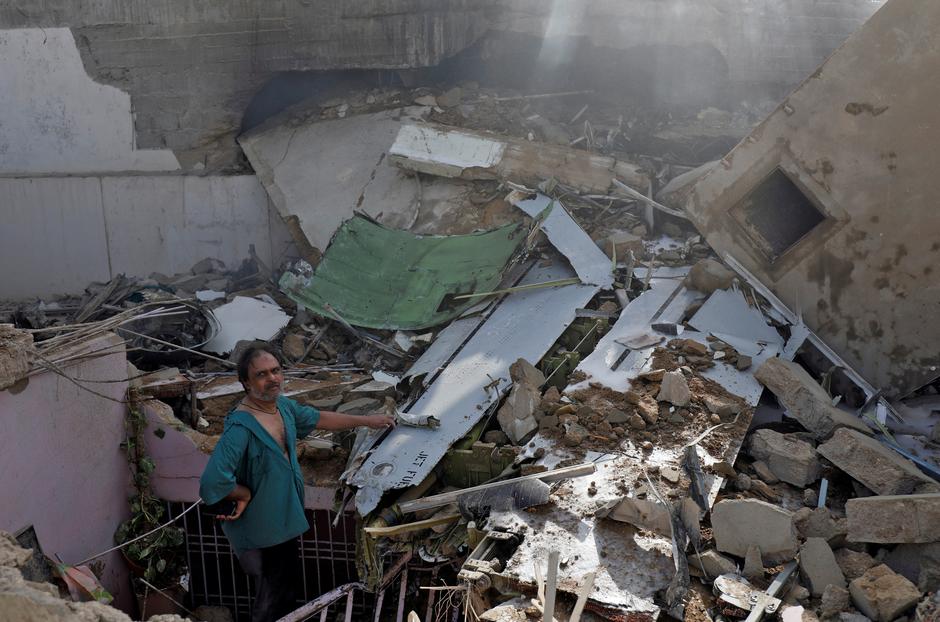 A man stands on the debris of a house at the site of a passenger plane crash in a residential area near an airport in Karachi, Pakistan May 22, 2020. REUTERS/Akhtar Soomro
