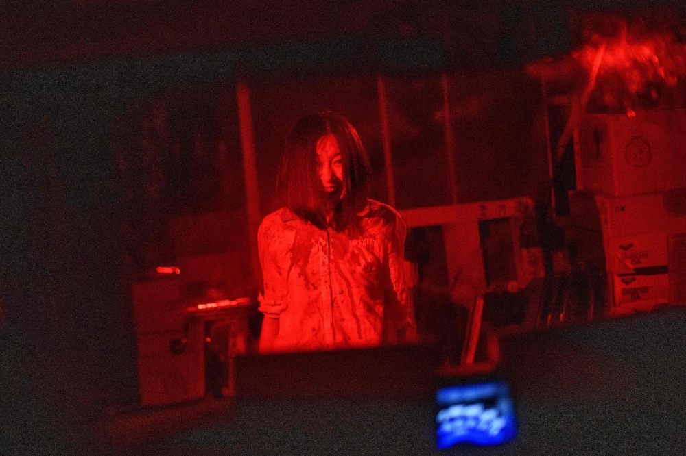 This picture taken on June 15, 2020 shows actress Asami Takeuchi, 33, performing during a murder scene at a demonstration of a haunted house at a garage in Tokyo. AFP / Philip Fong 