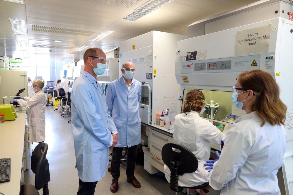 Britain's Prince William, Duke of Cambridge (2L), wearing PPE (personal protective equipment), of a face mask or covering, eye protection and an overall as a precautionary measure against spreading COVID-19, meets scientists including Christina Dold (R) d