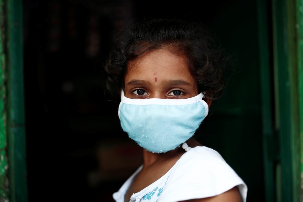 A girl wears a protective face mask in a slum area, during an extended nationwide lockdown to slow the spreading of the coronavirus disease (COVID-19), in New Delhi, India, June 24, 2020. REUTERS/Adnan Abidi