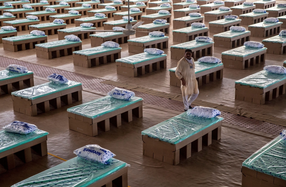 A volunteer walks past disposable beds made out of cardboard at the campus of Radha Soami Satsang Beas, a spiritual organization, where a coronavirus disease (COVID-19) care centre has been constructed for the patients amidst the spread of the disease, in