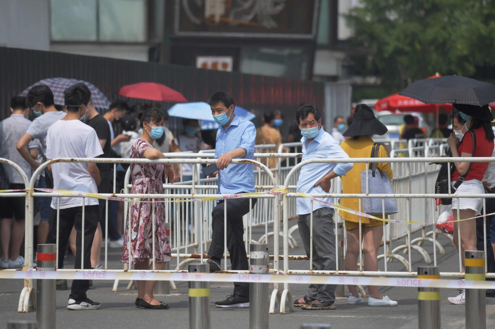People wear masks as they wait in line to undergo COVID-19 coronavirus swab tests at a testing station in Beijing on June 28, 2020.  AFP / GREG BAKER
