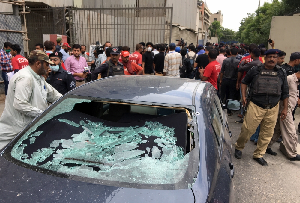 A plainclothes police officer (L) surveys the site of an attack at the Pakistan Stocks Exchange entrance in Karachi June 29, 2020. REUTERS/Akhtar Soomro
 