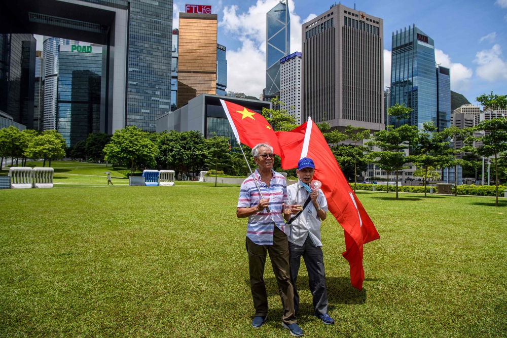 Pro-China supporters display Chinese and Hong Kong flags as they raise a toast with champagne during a rally near the government headquarters in Hong Kong on June 30, 2020, as China passed a sweeping national security law for the city.   AFP / Anthony WAL