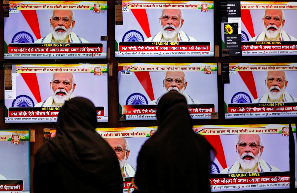 Women watch Indian Prime Minister Narendra Modi address the nation amid the spread of the coronavirus disease (COVID-19), on TV screens inside a showroom in Ahmedabad, India, June 30, 2020. REUTERS/Amit Dave

