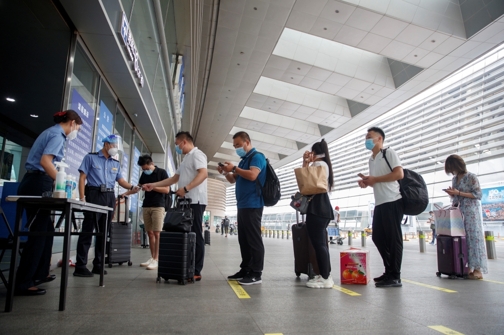 Station staff wear protective gear as they check the ID and health status of travellers before they enter the Beijing South Railway Station, after an outbreak of the coronavirus disease (COVID-19), in Beijing, China July 3, 2020. REUTERS/Thomas Peter
