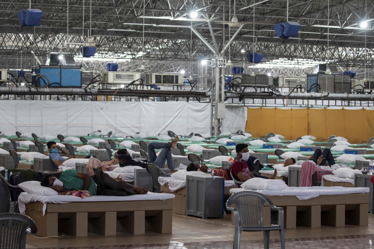 Patients rest laying on beds made out of cardboard inside the campus hall of spiritual organisation Radha Soami Satsang Beas (RSSB), converted into a COVID-19 coronavirus care centre, in New Delhi. on July 6, 2020. / AFP / Xavier GALIANA
