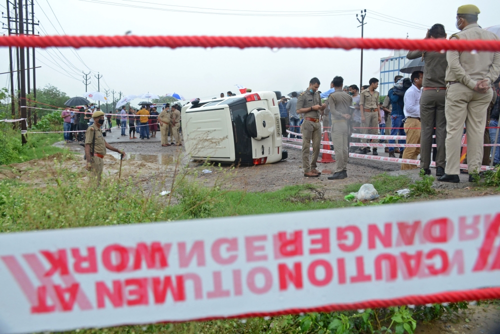 Policemen stand guard next to an overturned vehicle after the gangster Vikas Dubey was shot dead by police, on a highway at Sachendi in Uttar Pradesh state on July 10, 2020. / AFP / 