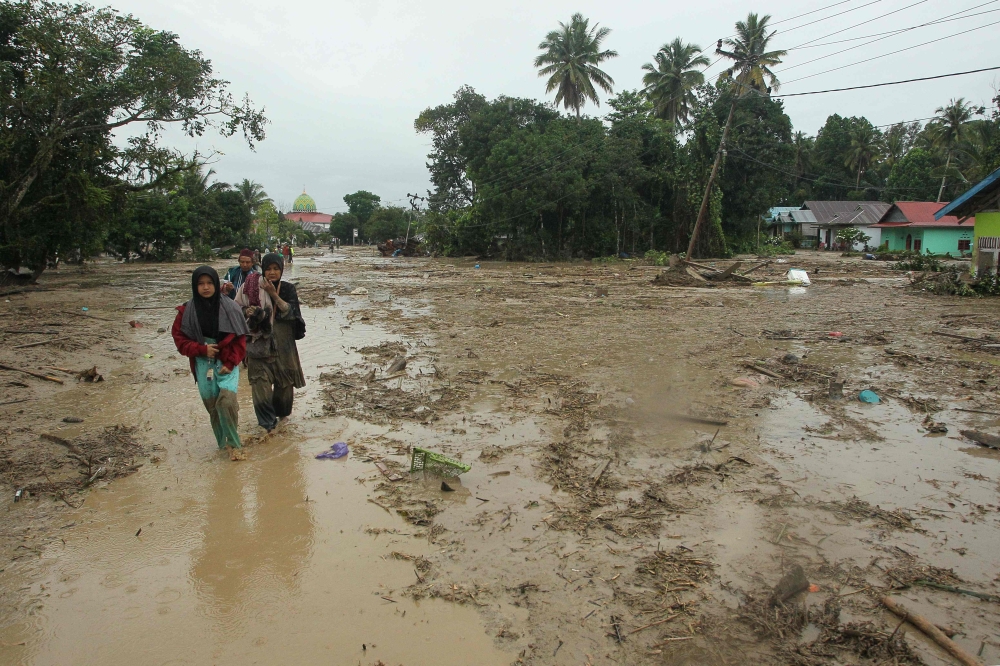 Villagers walk through a flooded area in Radda village in North Luwu regency, South Sulawesi on July 14, 2020, after three rivers overflowed due to torrential rains. AFP / Aryanto