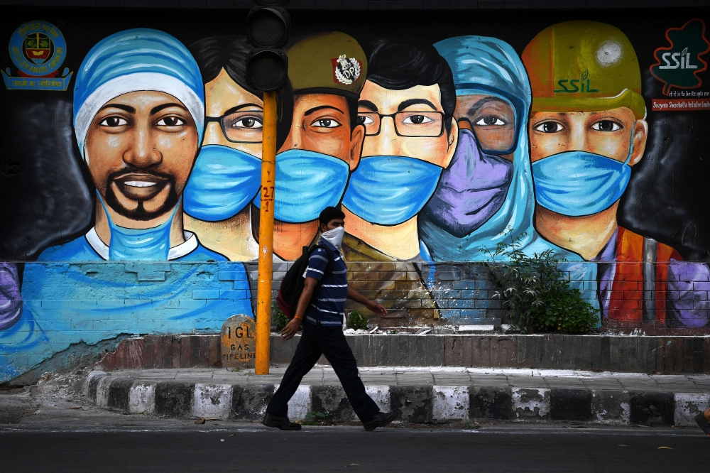 A man walks past a mural of frontline workers after the government eased a nationwide lockdown imposed as a preventive measure against the COVID-19 coronavirus in New Delhi on July 14, 2020. / AFP / Sajjad HUSSAIN