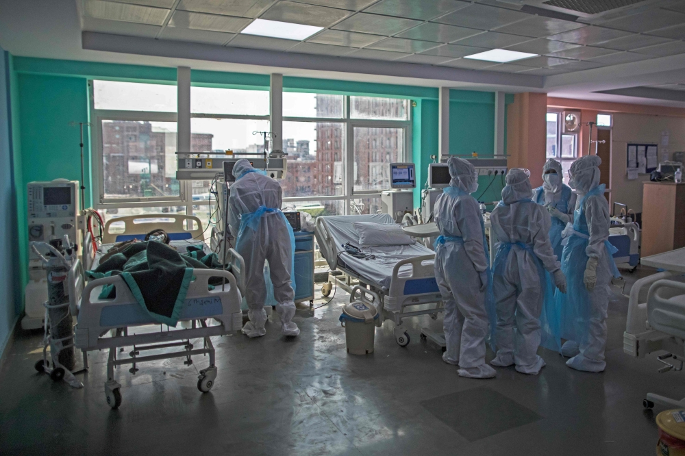 In this photograph taken on July 15, 2020 doctors and nurses wearing Personal Protective Equipment (PPE) gather next to a COVID-19 coronavirus patient at the Intensive Care Unit of the Sharda Hospital, in Greater Noida./ AFP / XAVIER GALIANA
