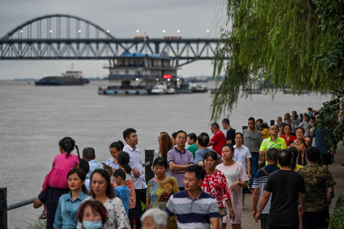 Residents look at the Yangtze River where the water level has risen in Jiujiang in China's central Jiangxi province on July 15, 2020. / AFP / Hector RETAMAL
