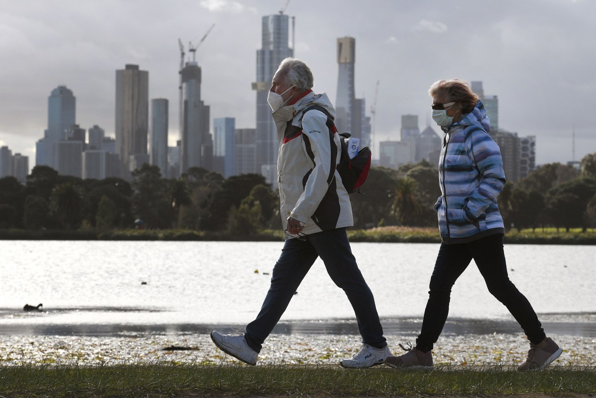 People walk along Albert Park lake in Melbourne on July 13, 2020, as five million people in Australia's second-biggest city began a new lockdown following a resurgence of coronavirus cases. / AFP / William WEST
