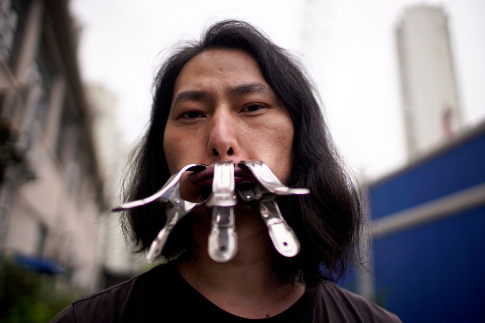 Brother Nut, Chinese performance artist with three metallic clips sealing his mouth, poses for a picture in Shanghai, following the coronavirus disease (COVID-19) outbreak, China July 13, 2020. Picture taken July 13, 2020. REUTERS/Aly Song
