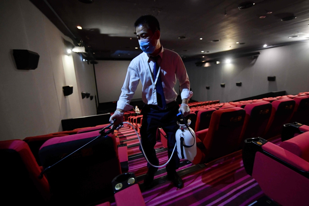 A worker disinfects a cinema in Beijing on July 20, 2020. Hundreds of cinemas reopened in scores of Chinese cities on July 20 following a nearly six-month nationwide shutdown due to the coronavirus. AFP / GREG BAKER