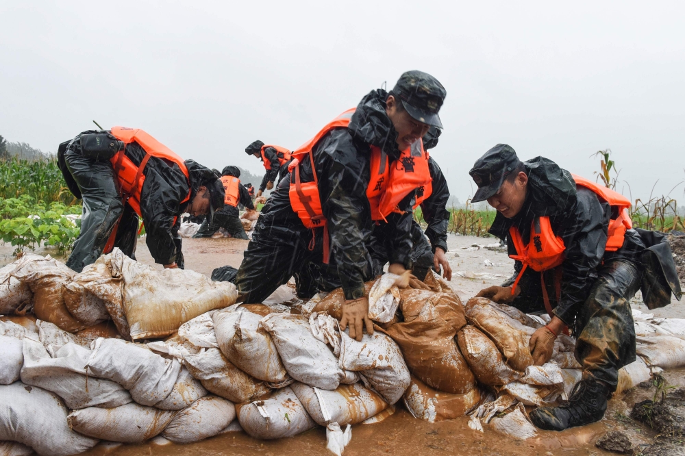 This photo taken on July 15, 2020 shows China's paramilitary police officers placing sandbags on a levee in the rain near the Yangtze River in Tongling in China's eastern Anhui province. The vast Yangtze drainage area has been lashed by torrential rains s