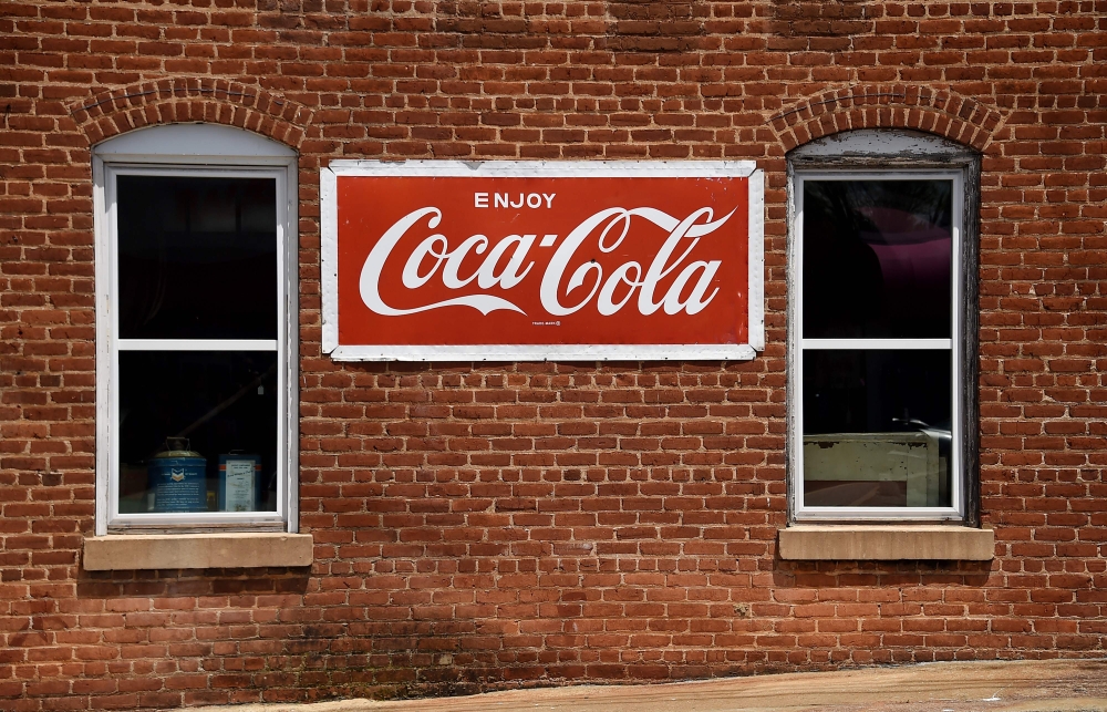 In this file photo a Coca Cola sign is seen in front of a store in Amherst, Virginia on May 9, 2020. Coca-Cola reported a steep drop in second-quarter profits on July 21, 2020 due to a big decline in away-from-home consumption, especially at the height of