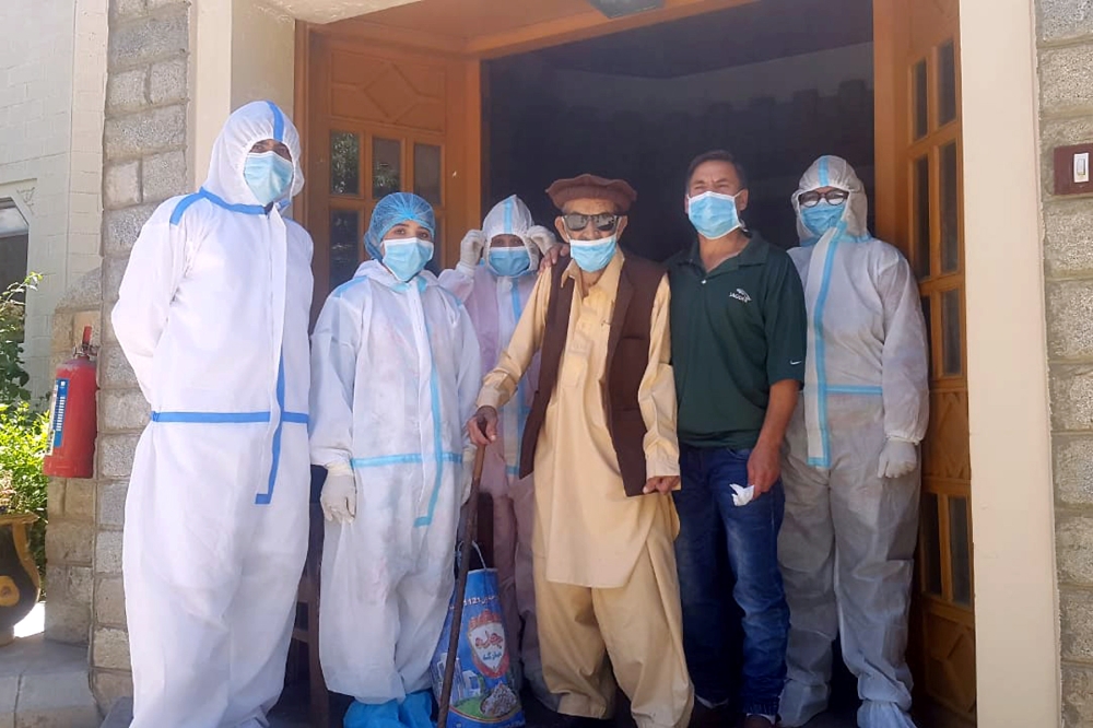 Abdul Alim, 103, stands with his son Suhail Aziz and staff members wearing personal protective equipment (PPE) in this group photograph taken after he recovered from coronavirus disease (COVID-19) and was discharged from the Aga Khan Health Services Emerg