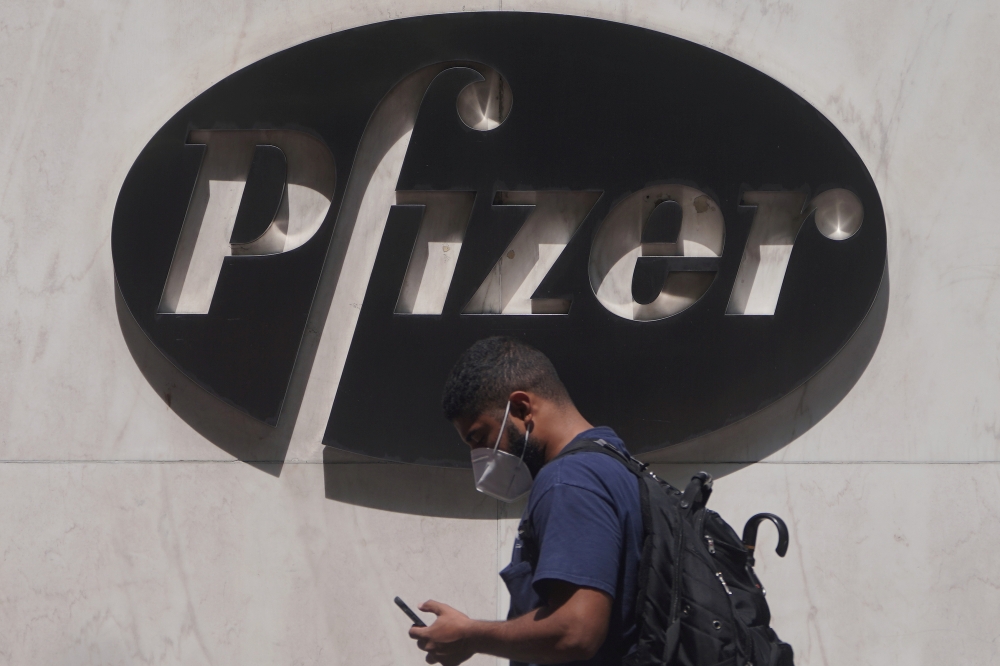 FILE PHOTO: A man walks past a sign outside Pfizer Headquarters in the Manhattan borough of New York City, New York, U.S., July 22, 2020. REUTERS/Carlo Allegri/File Photo