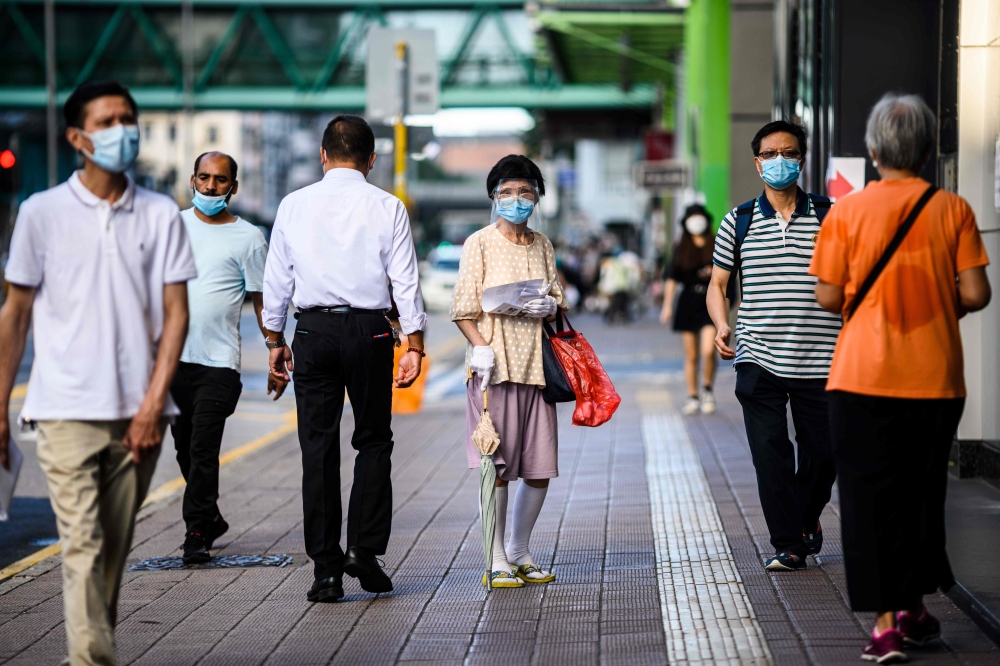 Pedestrians wear face masks in the Kowloon-side Sham Shui Po district of Hong Kong in the early morning of July 29, 2020, as new social distancing measures come into effect which include having to wear masks in public, to combat a new wave of coronavirus 
