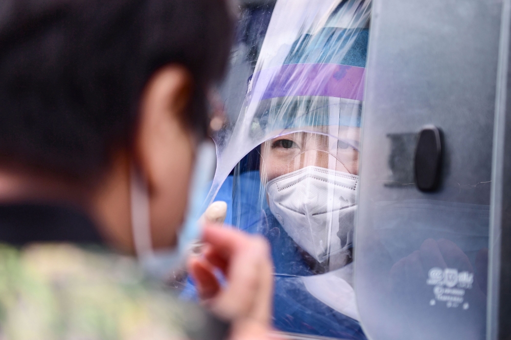A health worker carries out a COVID-19 coronavirus test on a resident in a testing vehicle in Shenyang in China's northeastern Liaoning province on July 29, 2020. China OUT / AFP / STR