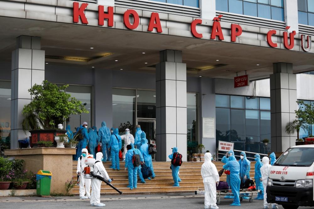 Vietnamese construction workers in blue protective suits, infected with the coronavirus disease (COVID-19), arrive at the tropical diseases hospital after being repatriated from Equatorial Guinea via a specially-adapted Vietnam Airlines plane filled with 