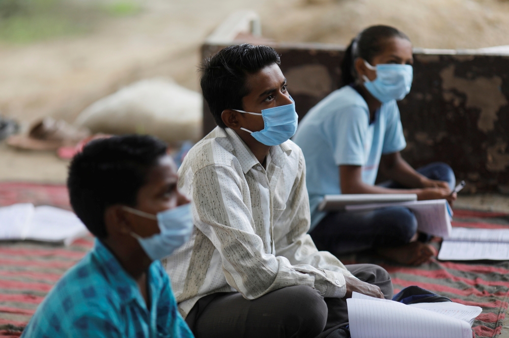 FILE PHOTO: Students of 9th class from a slum area, who do not have access to internet facilities and miss their online lessons, attend an open-air class taken by Satyendra Pal, a college student, after authorities closed all schools in March following th