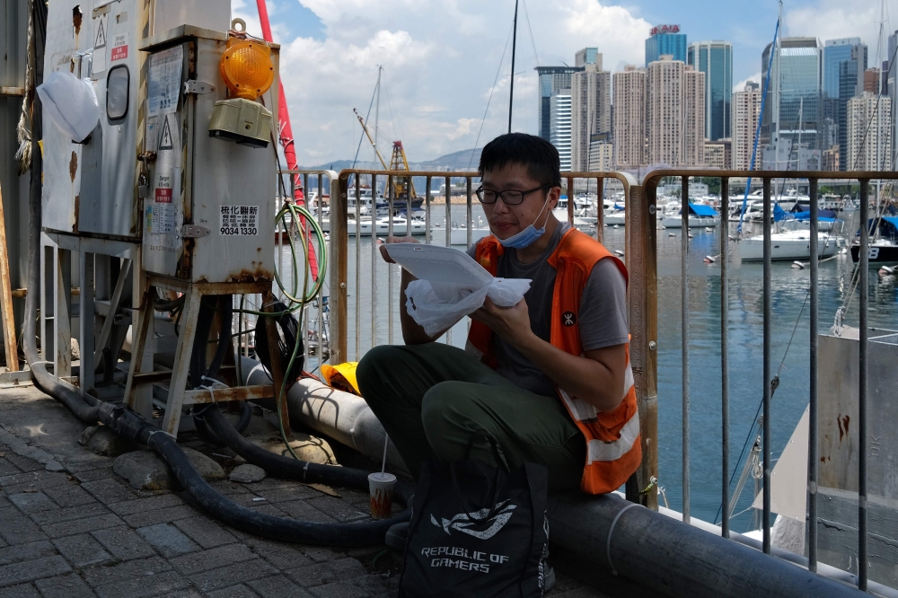 Kong, who works in construction, eats his takeaway lunch on a pavement in Hong Kong on July 29, 2020, after new social distancing measures came into effect which include restaurants only being allowed to serve takeaway meals, to combat a new wave of coron