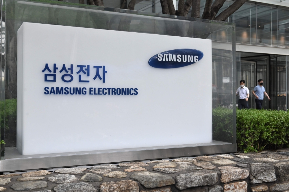 People walk past the logo of Samsung Electronics at the company's Seocho building in Seoul on July 30, 2020.  AFP / Jung Yeon-je
