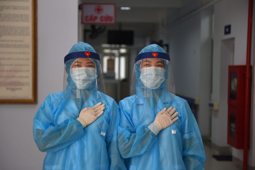Health workers wearing protective clothes pose for a photo at a temporary testing centre for the COVID-19 coronavirus in Hanoi on July 30, 2020. Until the weekend it appeared that Vietnam had managed to stub out the virus -- and with lockdowns lifted sinc