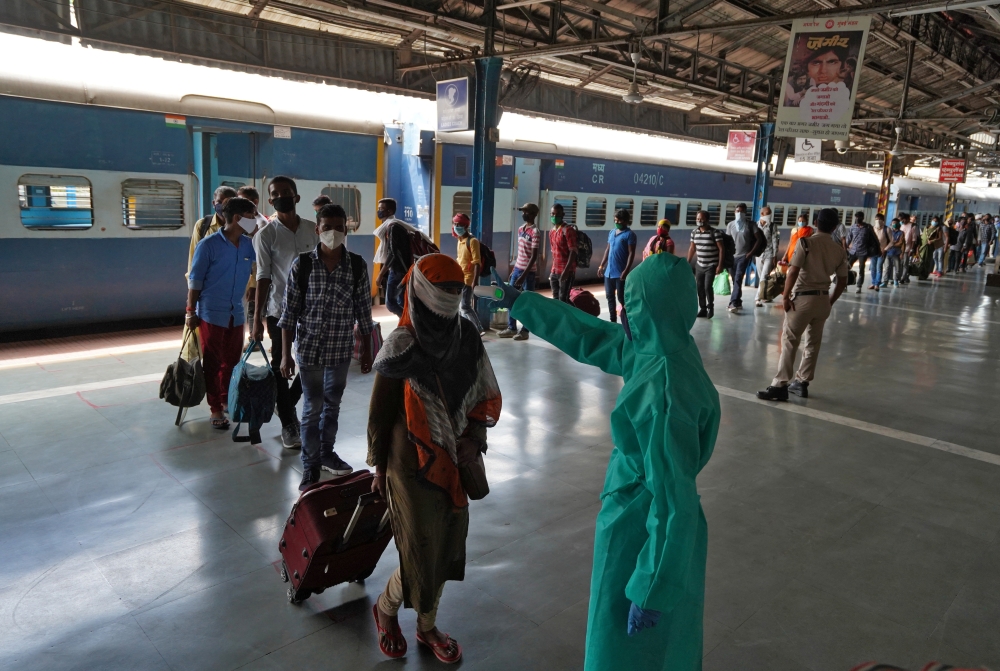 A worker wearing protective gear checks the temperature of a traveller at Dadar railway station, amidst the spread of the COVID-19 in Mumbai, India, July 31, 2020. (REUTERS/Hemanshi Kamani)