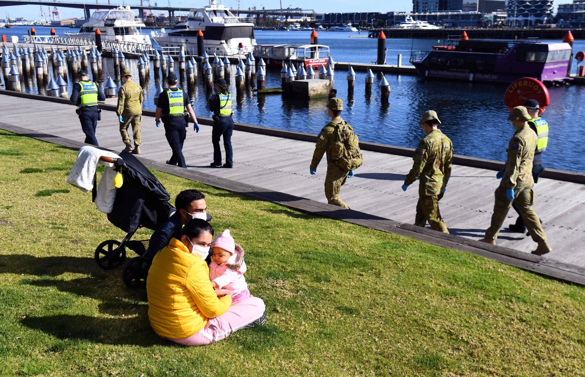 A group of police and soldiers patrol the Docklands area of Melbourne on August 2, 2020, after the announcement of new restrictions to curb the spread of the COVID-19 coronavirus. / AFP / William WES