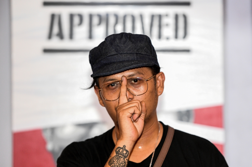 Headache Stencil, a graffiti artist poses in front of his works during his exhibition at The Foreign Correspondents' Club of Thailand (FCCT) in Bangkok, Thailand, July 31, 2020. Picture taken July 31, 2020. REUTERS/Chalinee Thirasupa