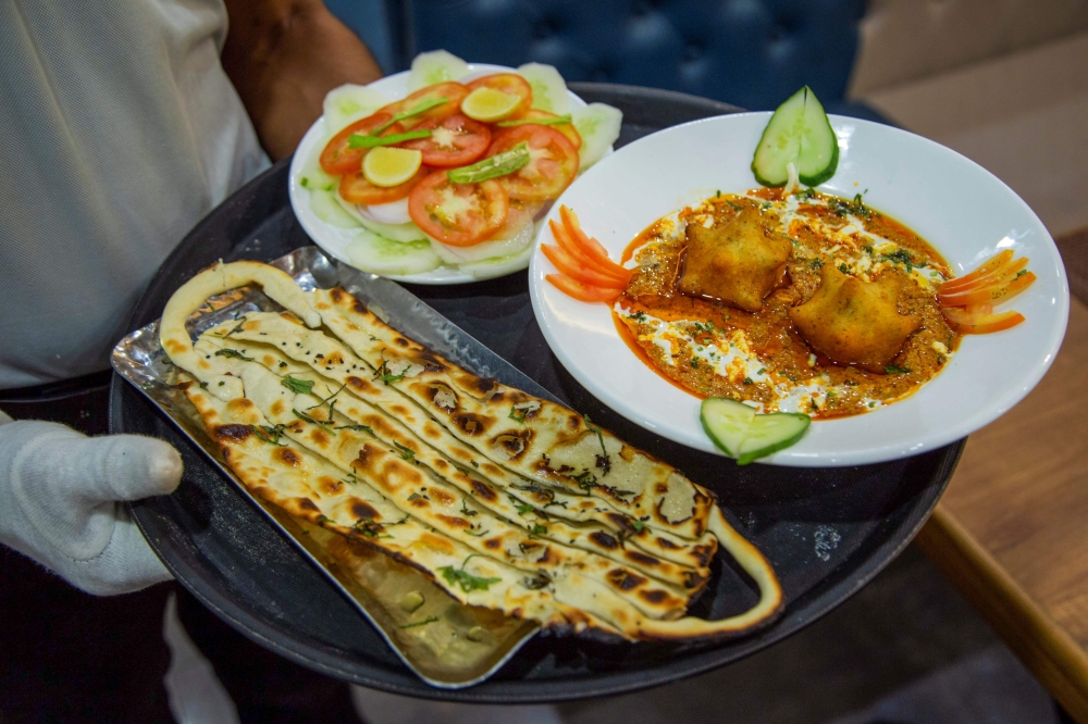 A waiter carries 'Covid Curry' and 'Mask Naan,' two Covid-19 coronavirus-themed dishes, to serve to customers at their restaurant in Jodhpur on August 3, 2020. / AFP / SUNIL VERMA