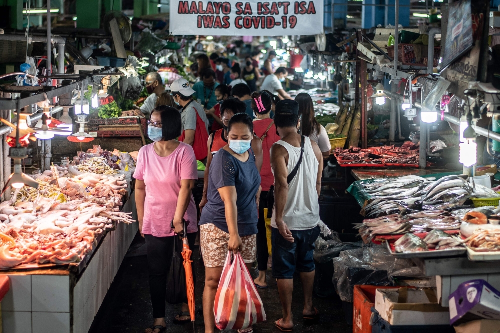 People wearing masks shop for fresh food at a market in Manila on August 6, 2020.  AFP / Lisa Marie David
