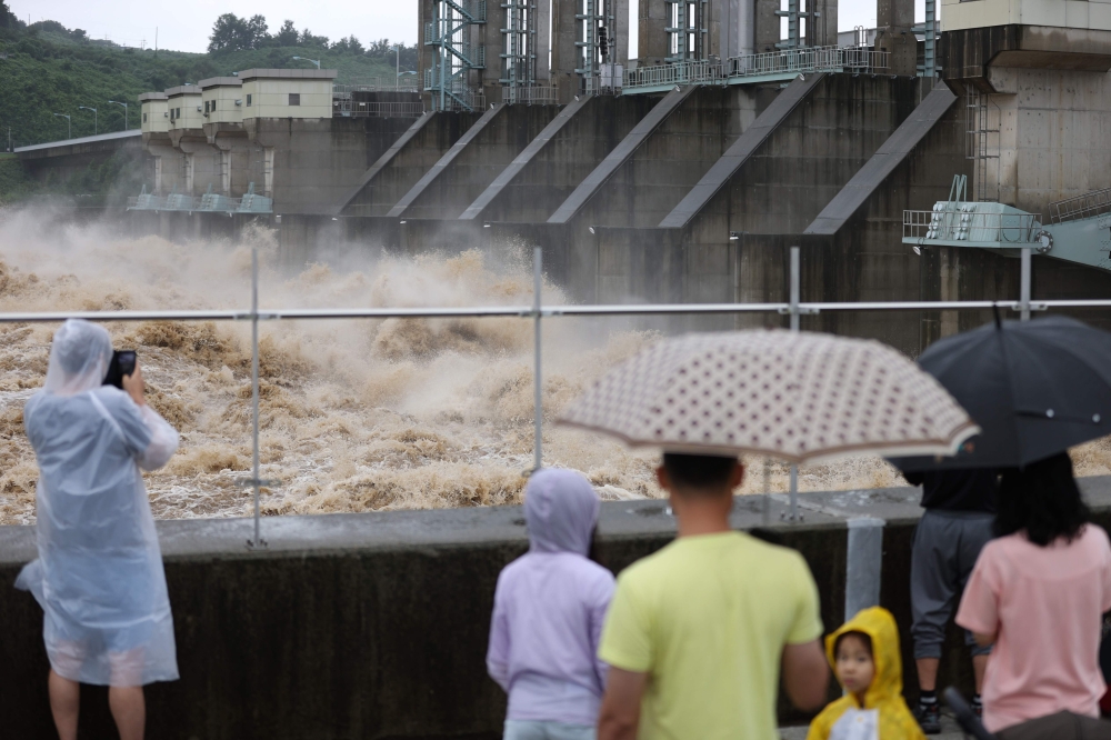 People watch as water from the Imjin river is discharged through the Gunnam Dam in Yeoncheon following heavy rain fall on August 6, 2020.  / AFP / YONHAP /