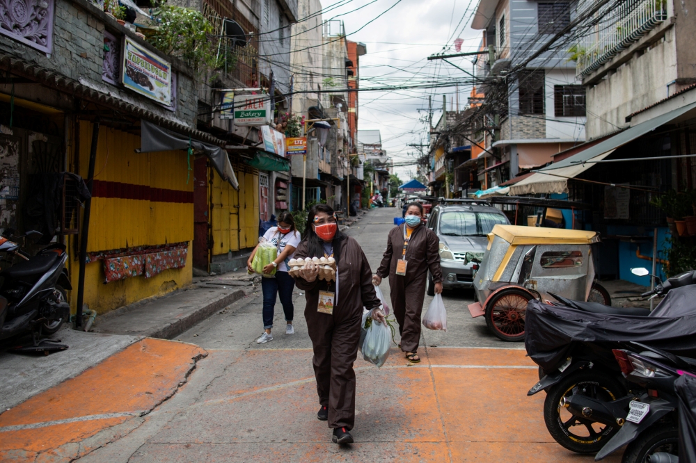 Government workers in hazmat suits sell fresh produce in a neighbourhood, amid the reimposed lockdown to curb the coronavirus disease (COVID-19) cases, in Navotas, Metro Manila, Philippines, August 6, 2020. REUTERS/Eloisa Lopez