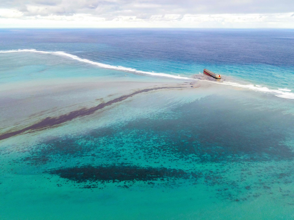 TOPSHOT - This aerial view taken on August 6, 2020 shows a large patch of leaked oil and the vessel MV Wakashio (R), belonging to a Japanese company but Panamanian-flagged, that ran aground near Blue Bay Marine Park off the coast of south-east Mauritius./