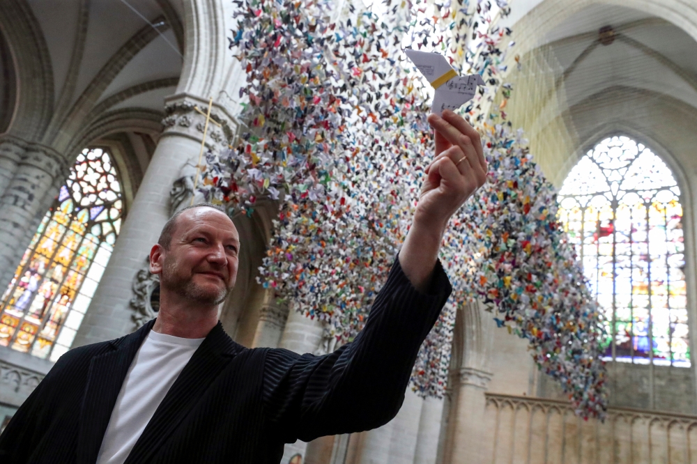 Belgian designer and artist Charles Kaisin poses next to an art installation made of 20,325 origamis called 