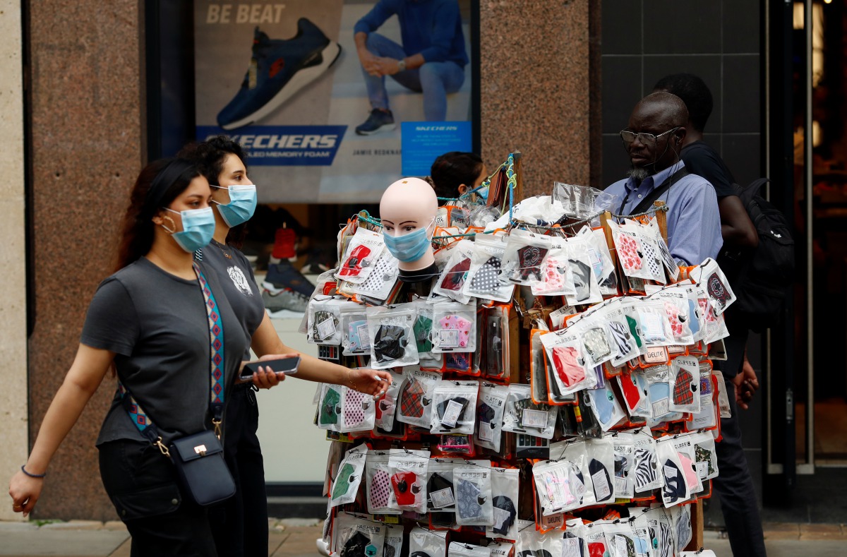 Women walk by a man selling face masks in Manchester city centre, following the outbreak of the coronavirus disease (COVID-19), Manchester, Britain, August 10, 2020. REUTERS/Jason Cairnduff
