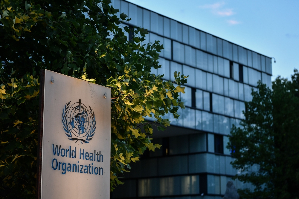 A photo taken in the late hours of August 17, 2020 shows a sign of the World Health Organization (WHO) at their headquarters in Geneva amid the COVID-19 outbreak, caused by the novel coronavirus. / AFP / Fabrice COFFRINI