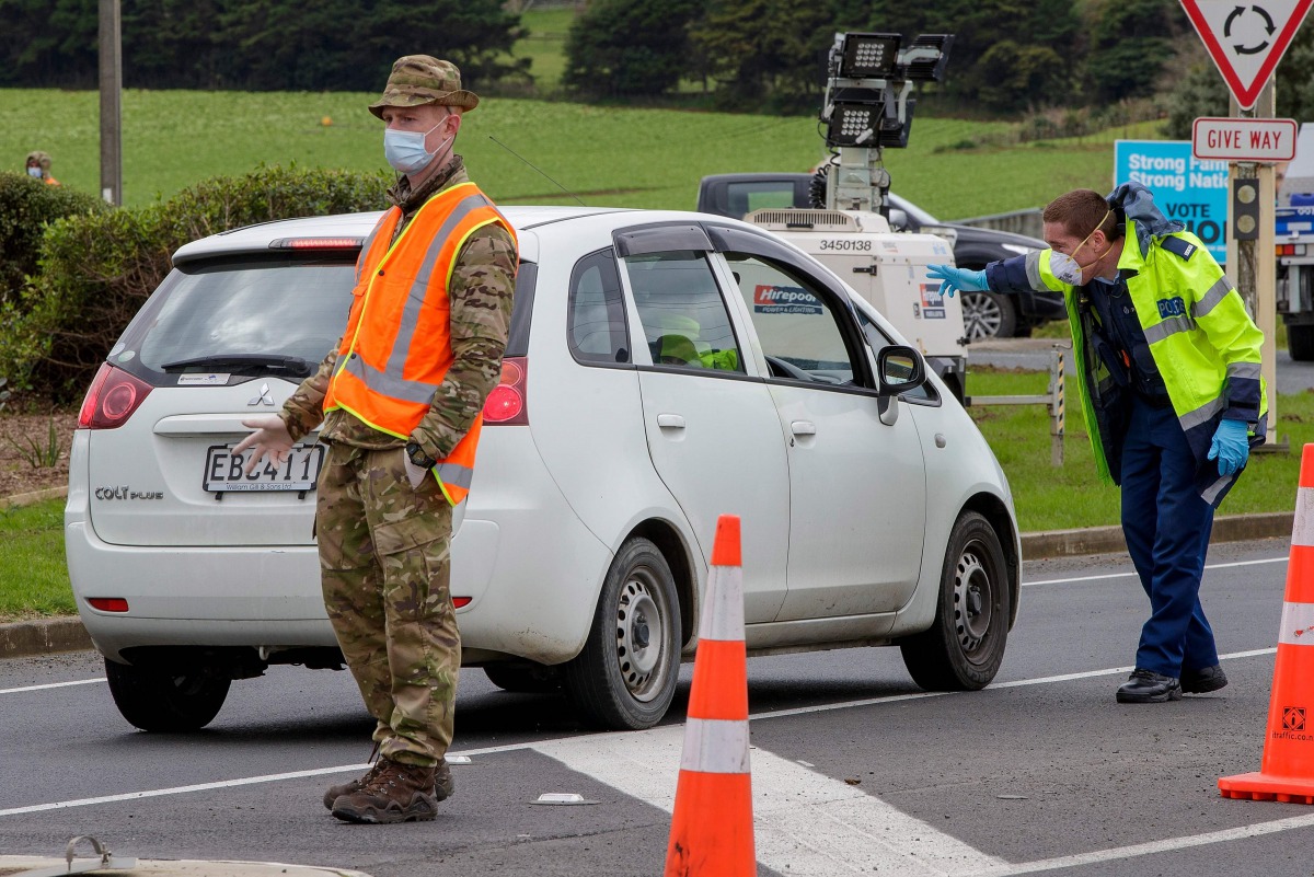 Police and military personnel check vehicles leaving the city at a COVID-19 check point setup at the southern boundary in Auckland on August 14, 2020. New Zealand rushed to track the source of a sudden return of the coronavirus as the number of new cases 