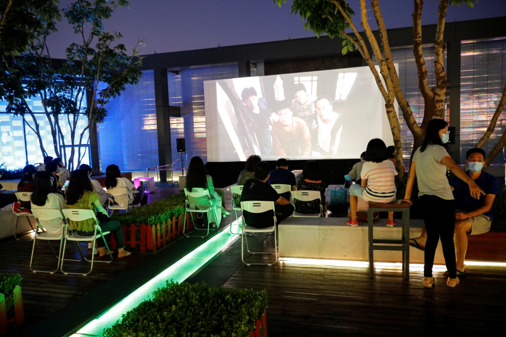 People watch a movie during a screening on a rooftop of a shopping mall on the opening night of the 10th Beijing International Film Festival that has been scaled down and largely moved online due to the outbreak of the coronavirus disease (COVID-19), in B